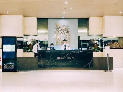 a reception desk in a shopping mall with two people at OKADA Pasay MOA 1257 DYNASTEL SHORE STAYCATION in Manila