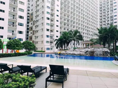 a large swimming pool with chairs and buildings at MALL OF ASIA 1656 Dynastel Shore Staycation in Manila
