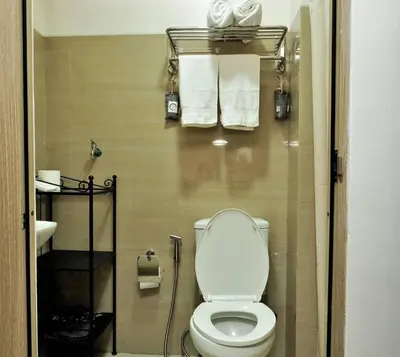 a bathroom with a toilet and towels on a wall at MALL OF ASIA 1656 Dynastel Shore Staycation in Manila