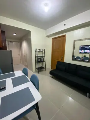a living room with a black couch and a table at Sea Residences MOA Pasay City - Ruffa's Condotel in Manila