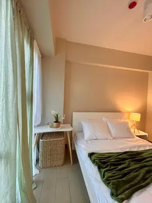 a bedroom with a bed and a table and a window at Condotel Across Naia T3 at ONE PALM TREE VILLA CLUSTER B in Manila