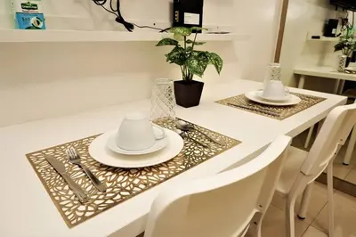 a table with two white plates and silverware on it at DYNASTEL 787 SHORE Staycation in Manila