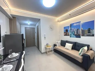 a living room with a blue couch and a kitchen at Pasay MOA 1486 Dynastel Shore Staycation in Manila