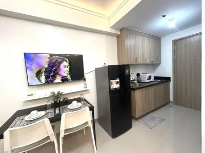 a kitchen with a table and a tv on the wall at Pasay MOA 1486 Dynastel Shore Staycation in Manila