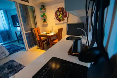 a kitchen with a counter and a dining room with a table at Cozy Chic Condotel Azure Urban Resort Residences in Manila