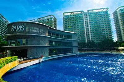 a building with a large pool in front of some buildings at Cozy Chic Condotel Azure Urban Resort Residences in Manila