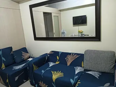 a living room with a blue couch and a mirror at MOA Condo by Ashti in Manila