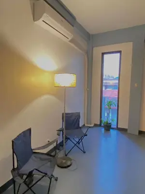 two chairs and a lamp in a room with a window at Lime Lite Manila Hostel in Manila