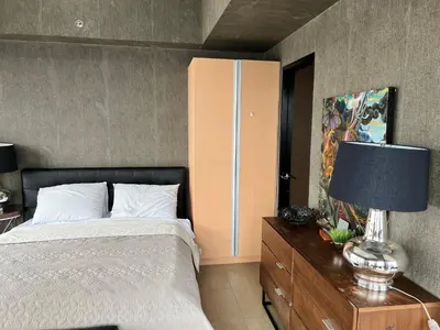 a bedroom with a bed and a lamp on a dresser at Modern Studio at NAIA Terminal 3 in Manila