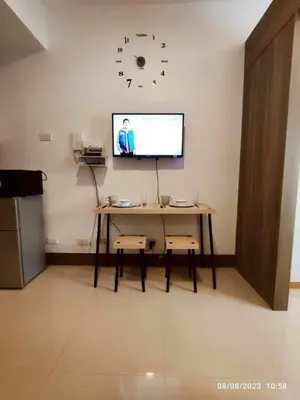 a room with a table and a clock on the wall at cozy studio unit at fame residence metro manila in Manila