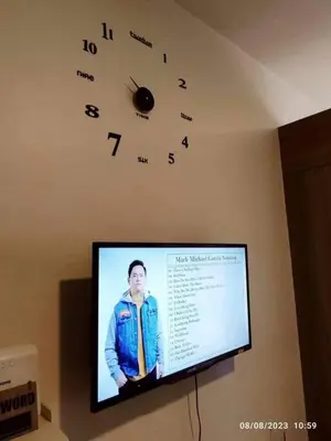 a tv on a wall with a clock on the wall at cozy studio unit at fame residence metro manila in Manila