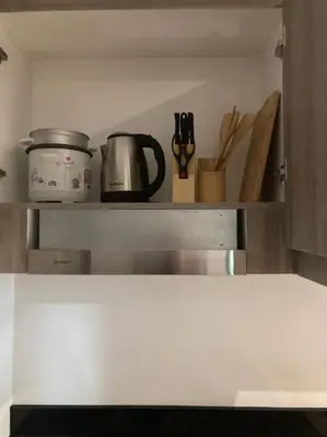 a shelf in a kitchen with some utensils at cozy studio unit at fame residence metro manila in Manila