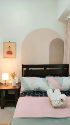 a bedroom with a bed and a table with a lamp at anuva residences room 1 in Manila