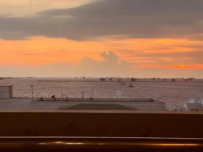 a sunset over the ocean with boats in the water at GRAND RIEVERA SUiTES in Manila