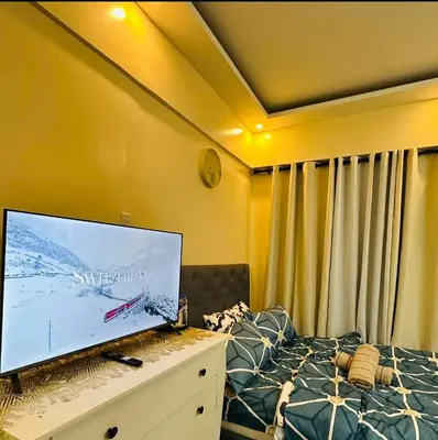 a bedroom with a large flat screen tv on a bed at Cozy Corner Haven near Venice Grand Canal Mall in Manila