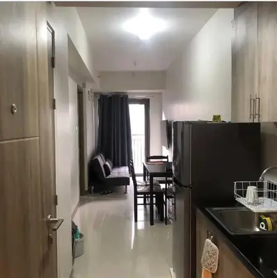 a kitchen with a black refrigerator and a living room at S Residence Condo Near MOA,IKEA in Manila