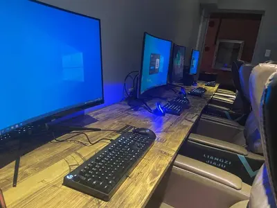 a desk with three computer monitors and a keyboard at Jjimjbang hotel spa in Manila