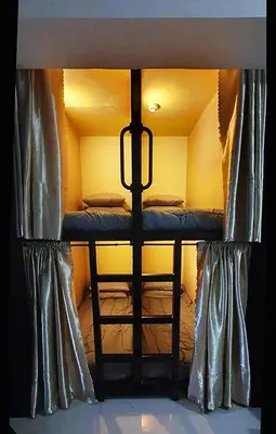 a bunk bed in a small room with curtains at C Place - Capsule A in Manila