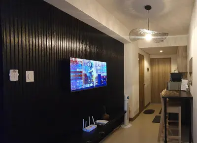 a living room with a tv on a black wall at C Place - Capsule A in Manila