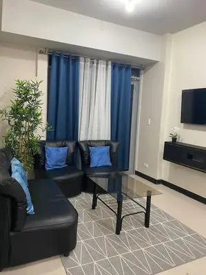 a living room with a couch and a glass table at Modern 1BR apartment in Manila