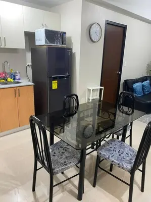 a glass table and chairs in a kitchen with a refrigerator at Modern 1BR apartment in Manila