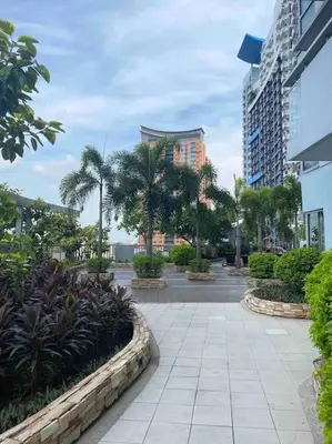 a walkway in a city with palm trees and buildings at Modern 1BR apartment in Manila