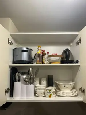 a kitchen shelf filled with dishes and utensils at Modern 1BR apartment in Manila