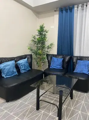 a living room with a black couch and blue pillows at Modern 1BR apartment in Manila