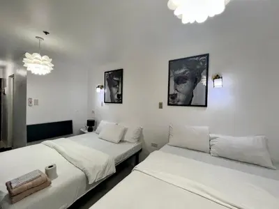 two beds in a room with white walls and chandeliers at Staycation Condotel Room to Stay Paranaque in Manila