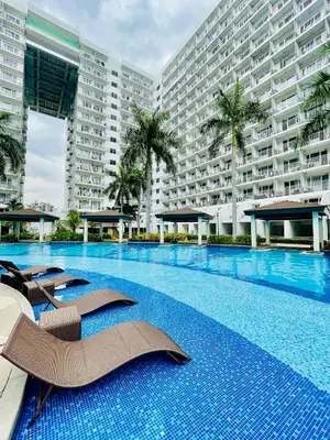 a swimming pool with chairs and a large building at Aiza's CondoTel in Shell Residences near MOA and NAIA in Manila