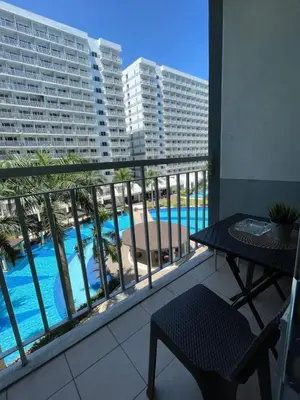 a balcony with a table and a view of a pool at Aiza's CondoTel in Shell Residences near MOA and NAIA in Manila
