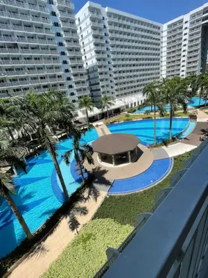 an overhead view of a pool with palm trees and buildings at Aiza's CondoTel in Shell Residences near MOA and NAIA in Manila