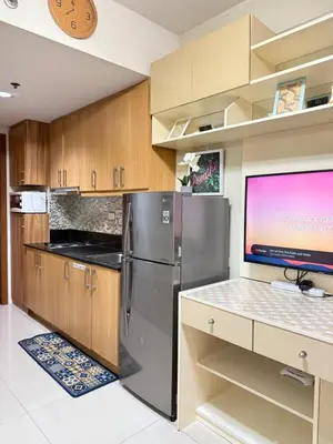 a kitchen with a refrigerator and a flat screen tv at Aiza's CondoTel in Shell Residences near MOA and NAIA in Manila