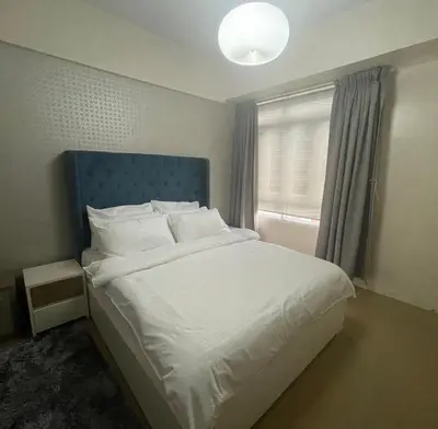 a bedroom with a bed with a blue headboard and a window at 150 Newport Boulevard, near Terminal3 Airport in Manila