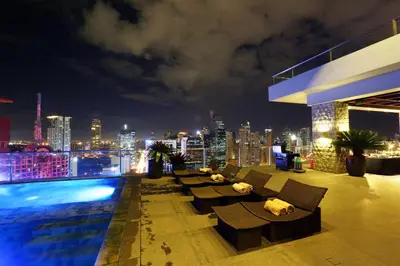 a rooftop patio with a view of a city at night at City Garden Grand Hotel in Manila