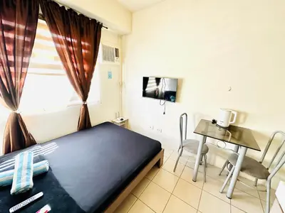a room with a bed and a table and a window at Fancy Condo with Unli Wifi and Netflix in Manila