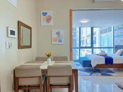 a room with a bed and a table and chairs at MODERN BGC 1BR, Uptown Mall Connector, 5G WiFi, Pool, Ste 17 in Manila