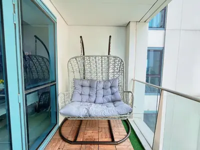 a wicker chair on a balcony with a purple pillow at HUGE 2BR BGC Suite 70sqm, Perfect for 6, Balcony, Pool & Uptown Mall Connector, Ste 25 in Manila
