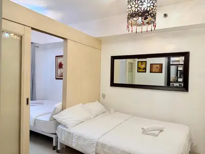 a bedroom with two beds and a mirror at PinkDoorZ MOA Staycation at SEA Residences in Manila