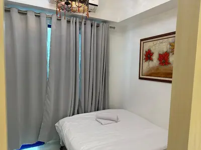 a bedroom with a bed and a window with curtains at PinkDoorZ MOA Staycation at SEA Residences in Manila
