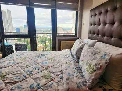 a bedroom with a bed with a quilt on it at KL Tower Cosy Studio with Balcony Sauna Gym Pool near Greenbelt in Manila