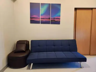 a blue couch and a chair in a room at BGC Cosy Spacious 1BR Uptown Parksuites with Balcony in Manila