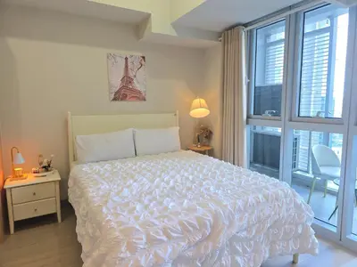 a bedroom with a large bed and a window at Cosy BGC Uptown Parksuites with Nice Balcony City View and Ultra Fast Internet 300mbps in Manila