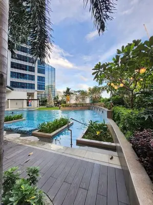 a large swimming pool with plants in a city at Cosy BGC Uptown Parksuites with Nice Balcony City View and Ultra Fast Internet 300mbps in Manila