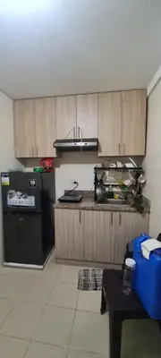 a kitchen with a black refrigerator and wooden cabinets at Arveelene Bedspacing in Manila