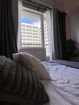 a bedroom with a bed and a window with a building at Grace Residences Elevate Escapes - near BGC airport in Manila