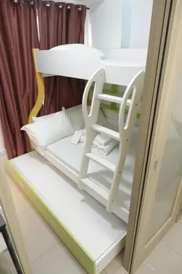 a bunk bed with white furniture in a room at Mall of Asia Shore Dynastel Staycation in Manila
