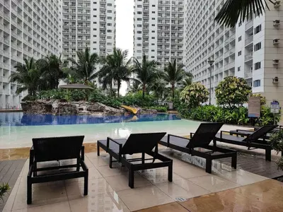 a pool in a building with chairs and palm trees at Mall of Asia Shore Dynastel Staycation in Manila