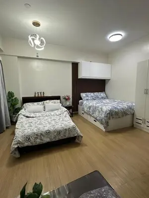 a bedroom with two beds and a chandelier at Davids Suite at Hope Residences Trece Martires Cavite in Trece Martires
