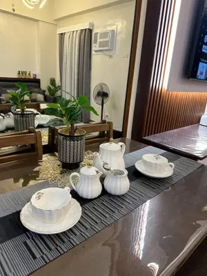 a table with three teapots and plates on it at Davids Suite at Hope Residences Trece Martires Cavite in Trece Martires